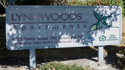 a sign apartments is shown in front of trees